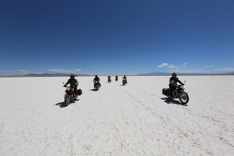 Motards Mono 500 traversant un salar blanc sur l'Altiplano argentin, une destination de road trip moto