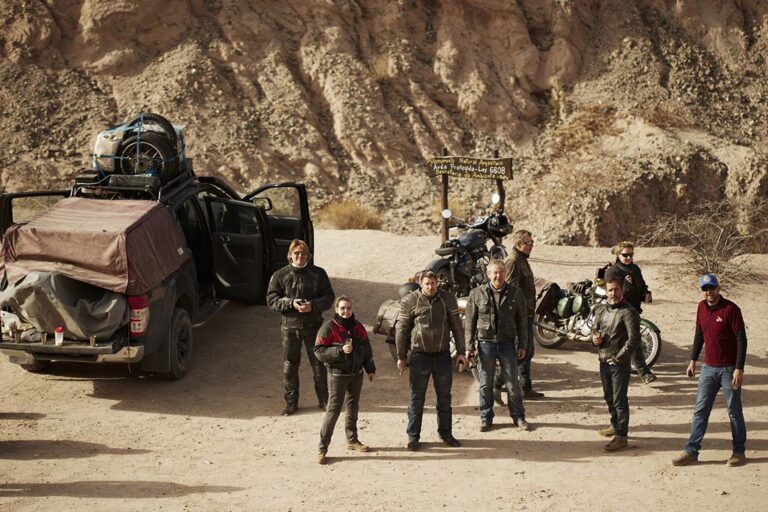Groupe de voyageurs et véhicule d'assistance sur une piste du Nord-Ouest argentin pendant un voyage moto accompagné
