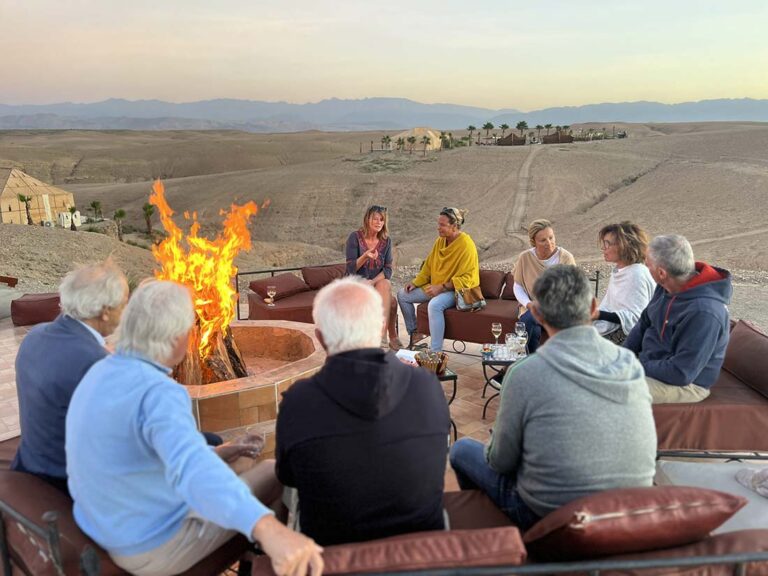 Voyageurs Mono 500 réunis autour d'un feu au coucher du soleil dans le désert marocain