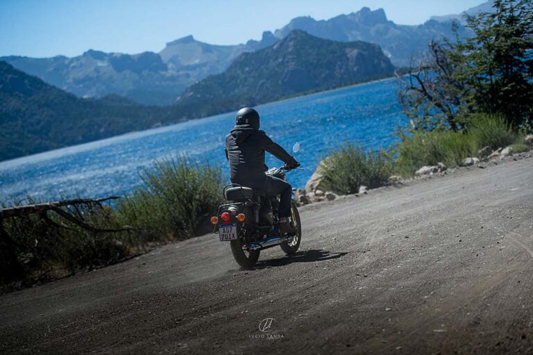 Motard sur une route au bord d'un lac en Patagonie, voyage à moto avec la responsabilité civile de la moto incluse