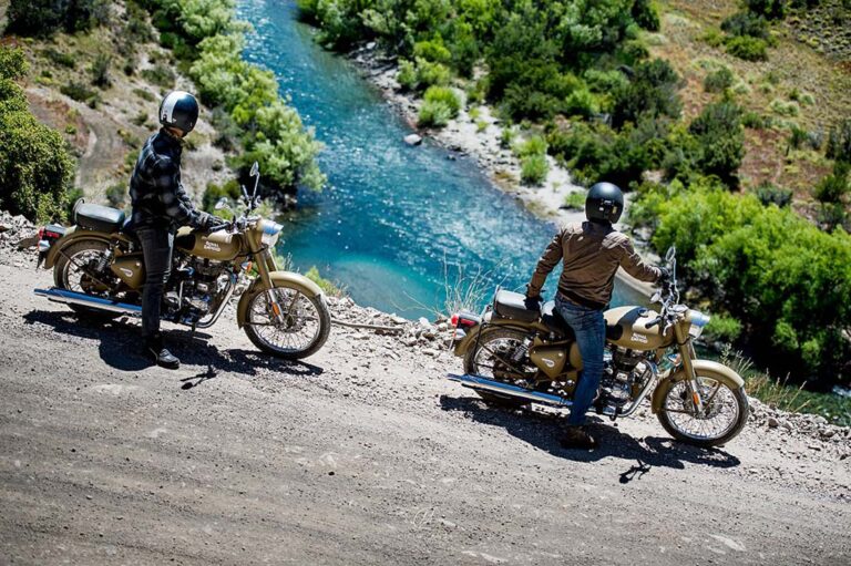 Deux voyageurs et leurs Royal Enfield au bord d'une rivière turquoise en Patagonie