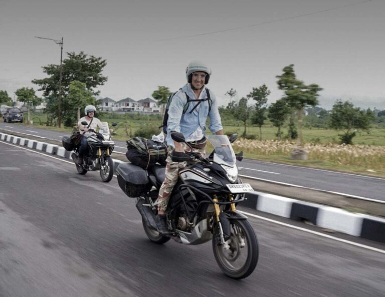 Motard souriant sur une route d'Indonésie, une destination asphaltée pour un road trip moto en famille