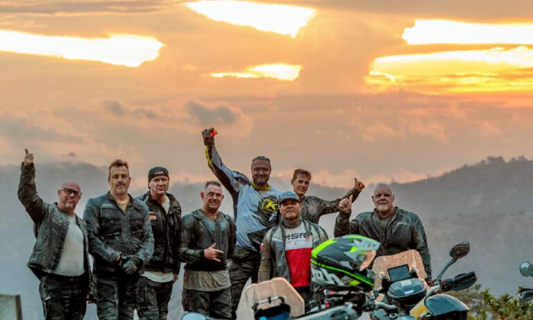 Bande d'amis motards célébrant au coucher du soleil pendant un road trip moto entre amis en Colombie